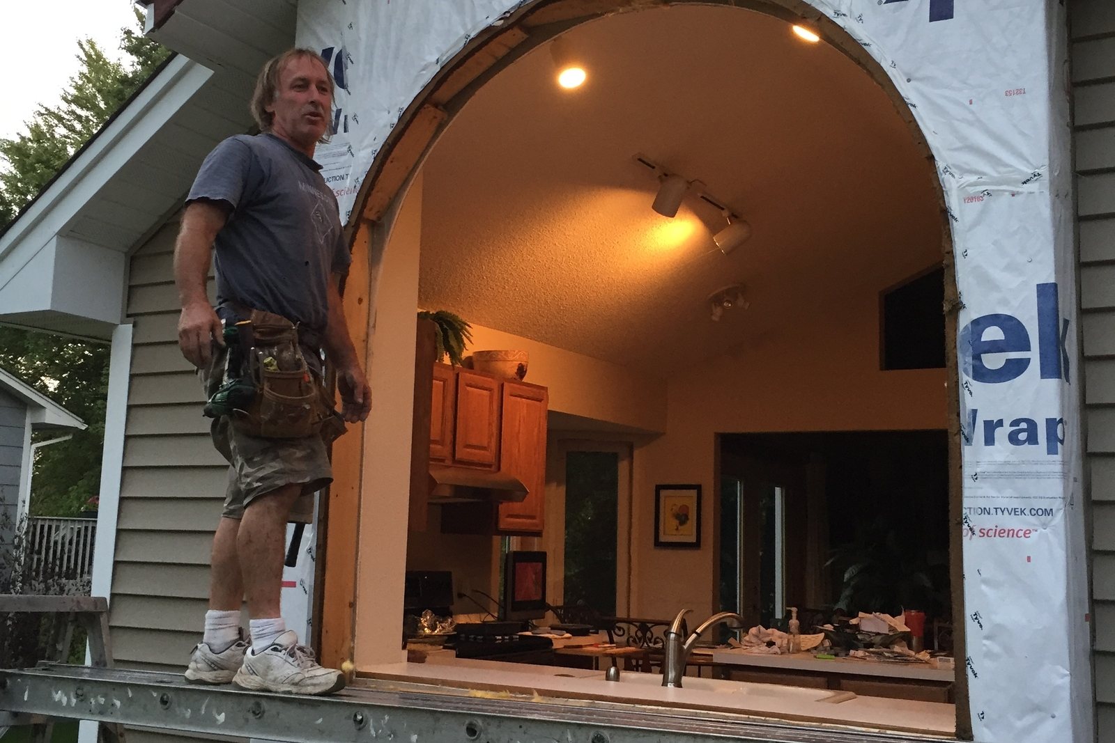Crew member fitting a replacement window into an open wall on a Twin Cities home