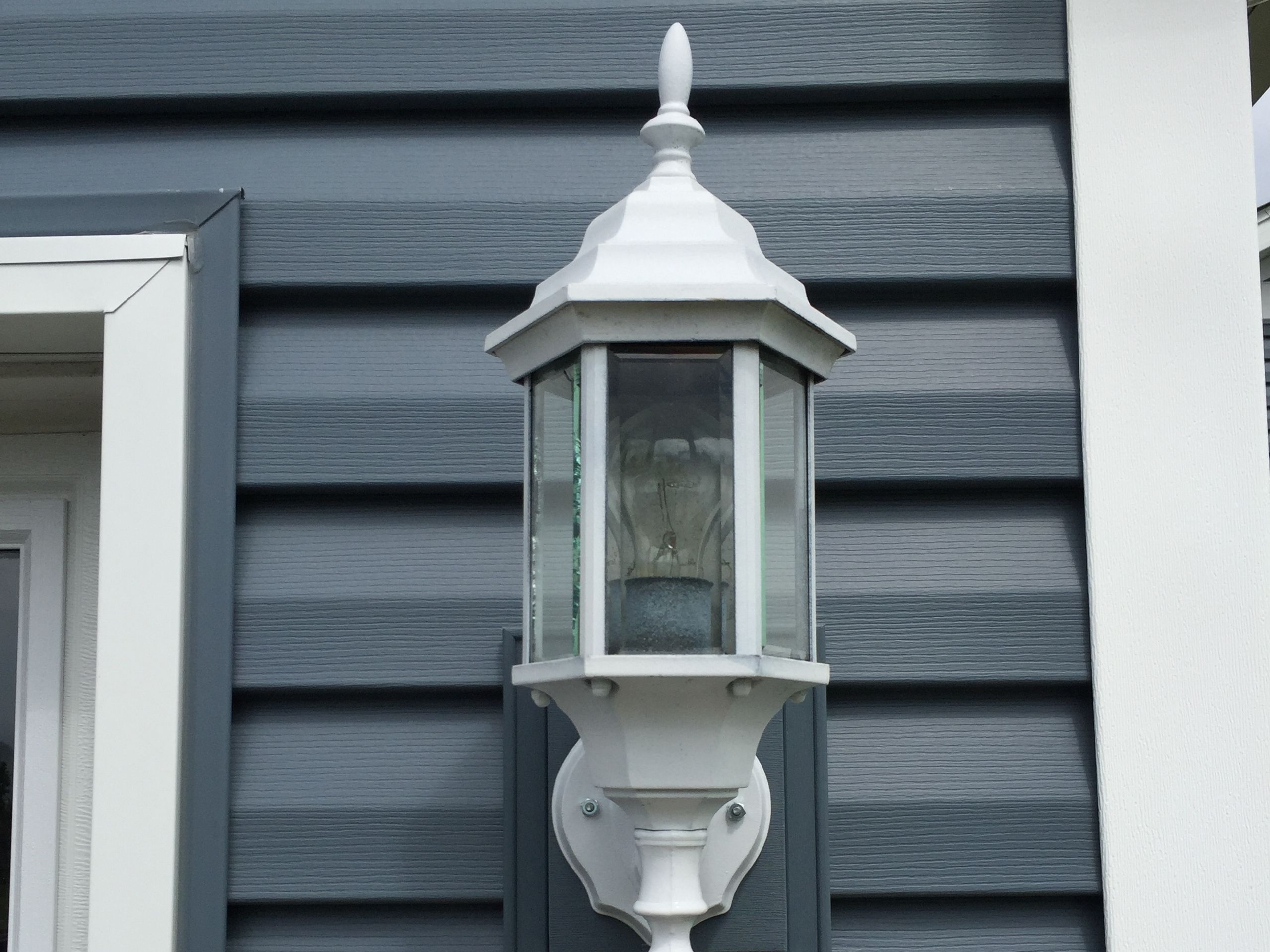 White coach light mounted on new blue-gray lap siding
