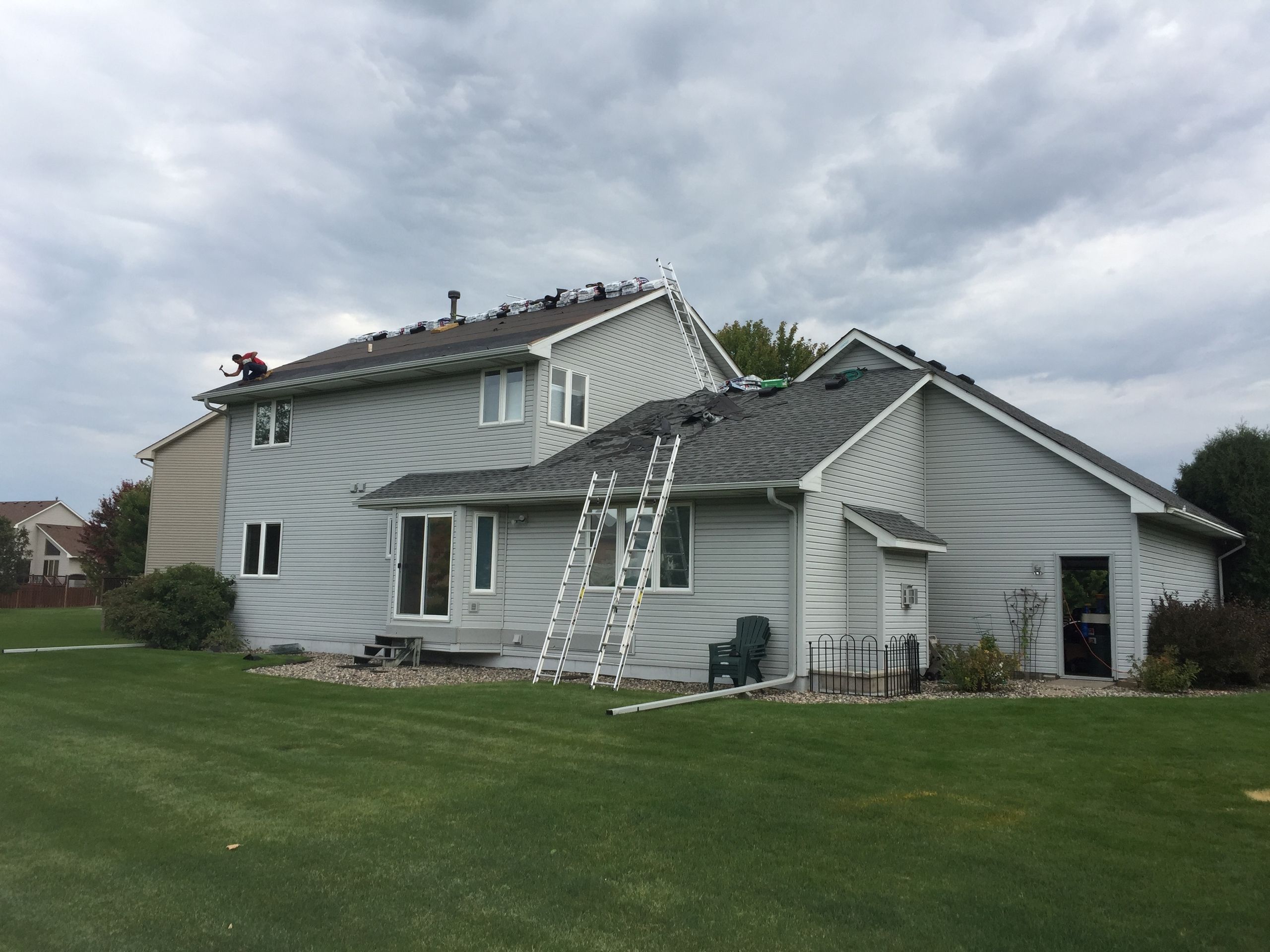 Two-story home partway through a re-side with ladders in place