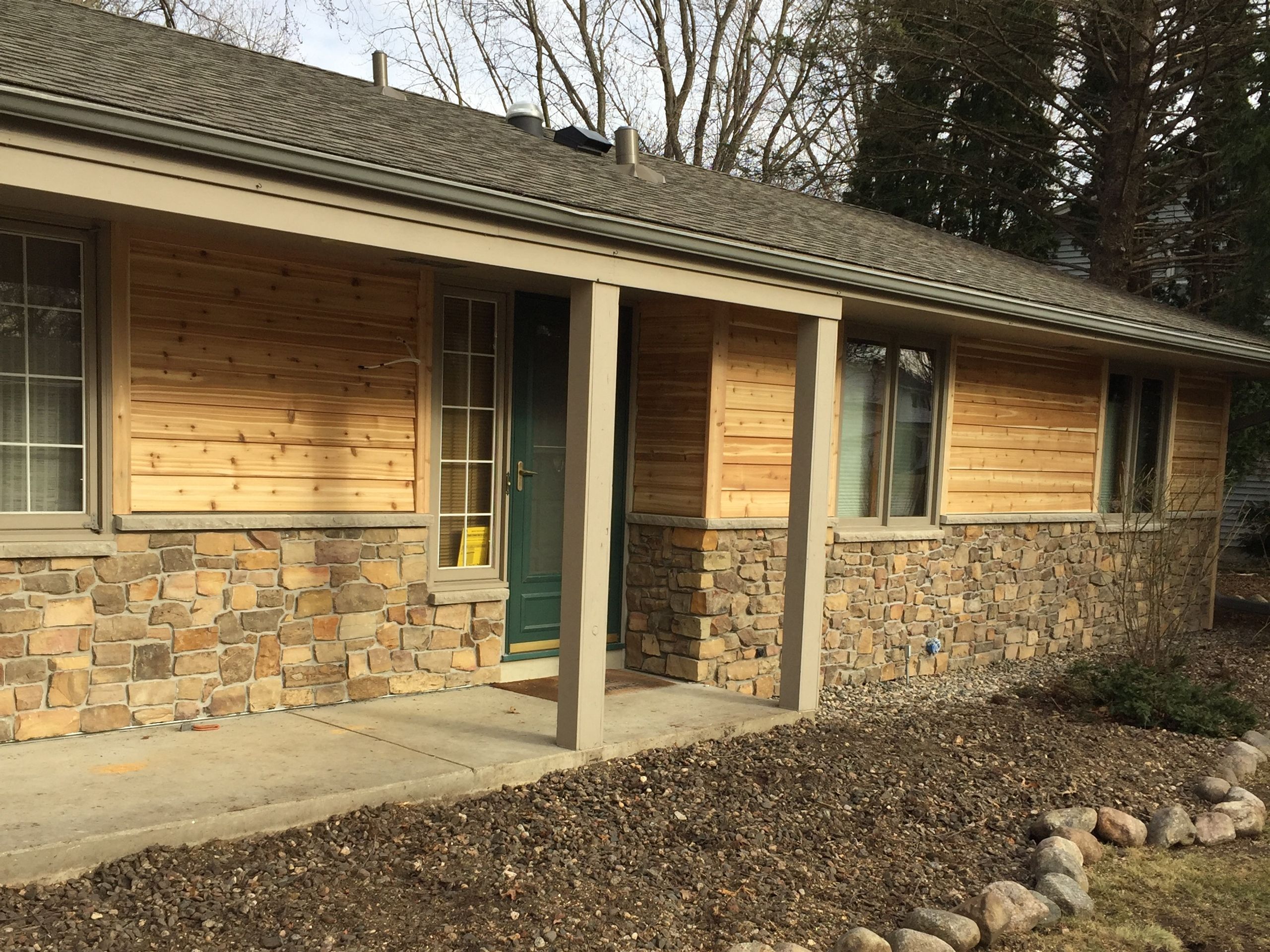 Ranch home with natural cedar siding above a stone base