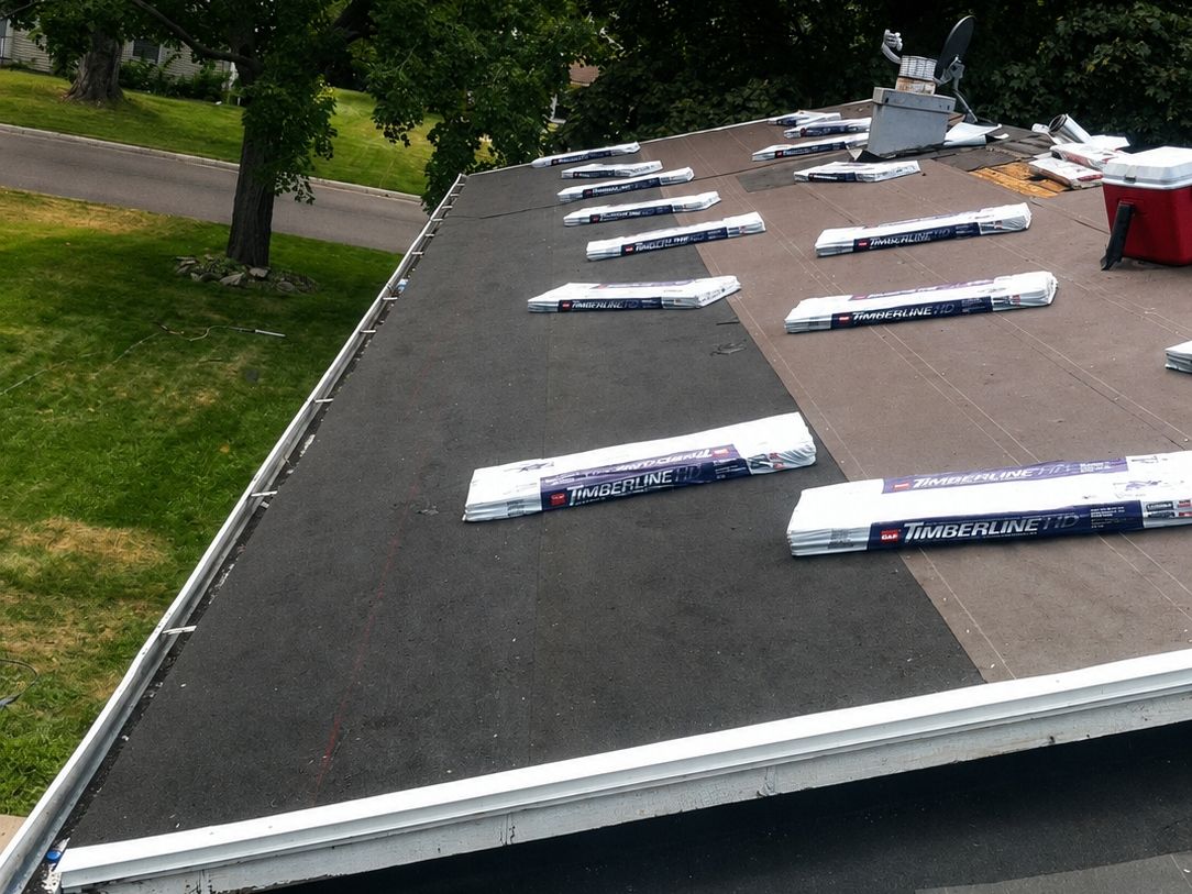 Shingle bundles staged on a low-slope roof with underlayment down