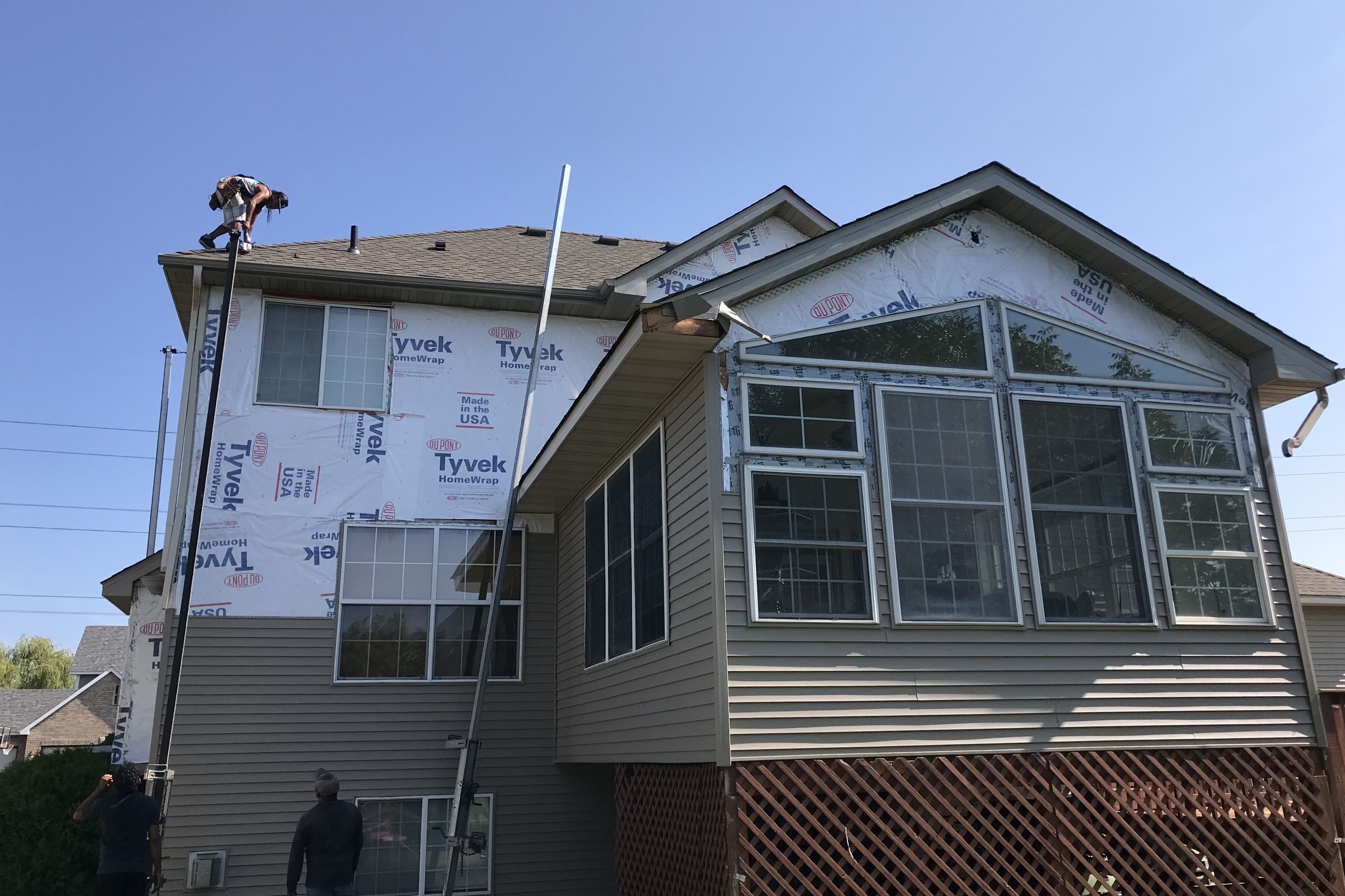 Two-story home wrapped in house wrap with new windows set, ready for siding