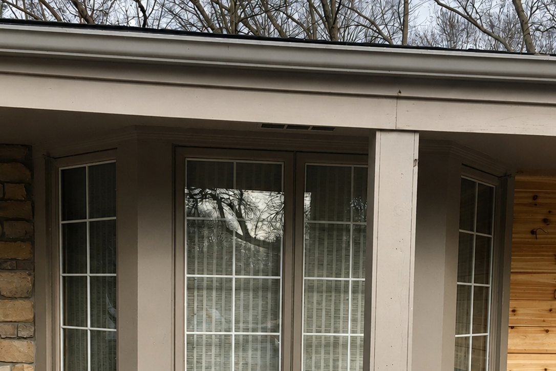 Bay window wrapped in new trim beside natural cedar siding