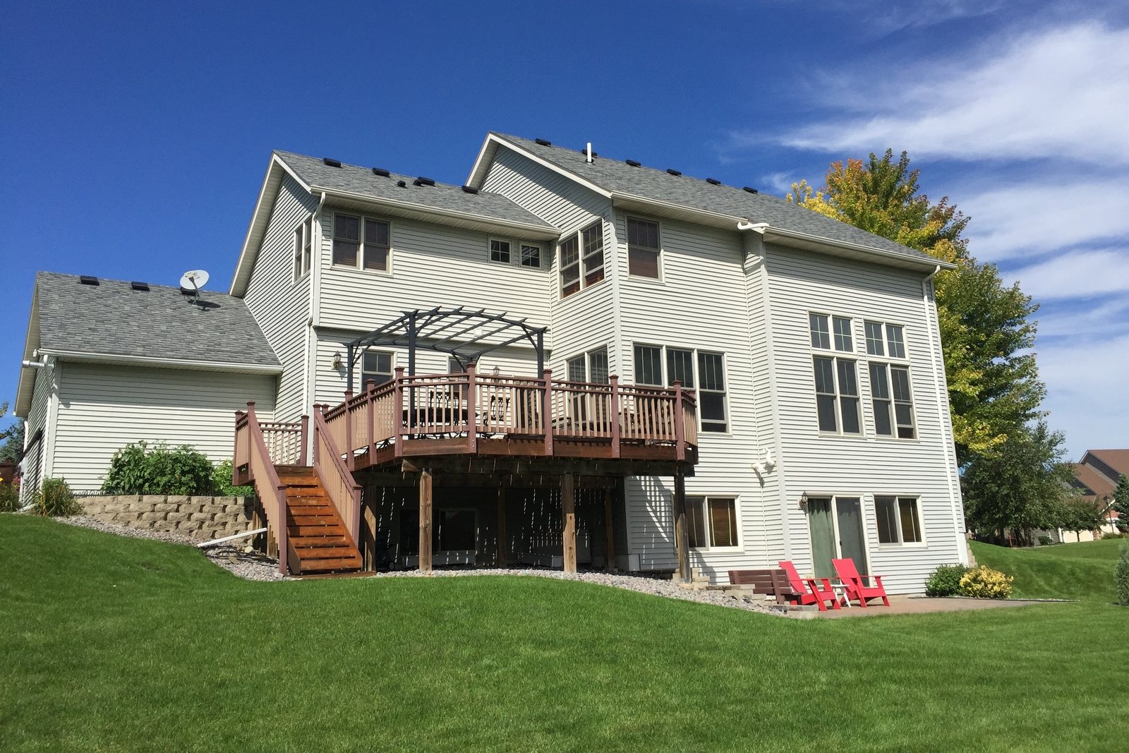 Two-story home re-sided in cream lap siding above a raised deck