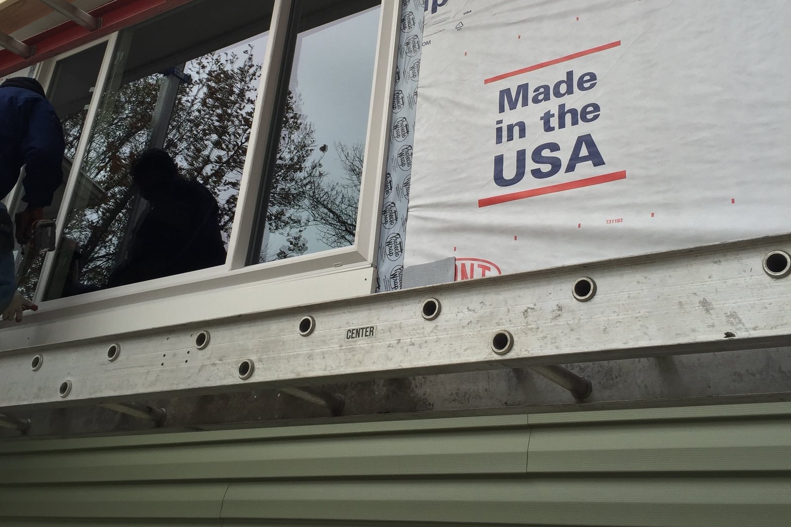 Two installers guiding a new window into its opening