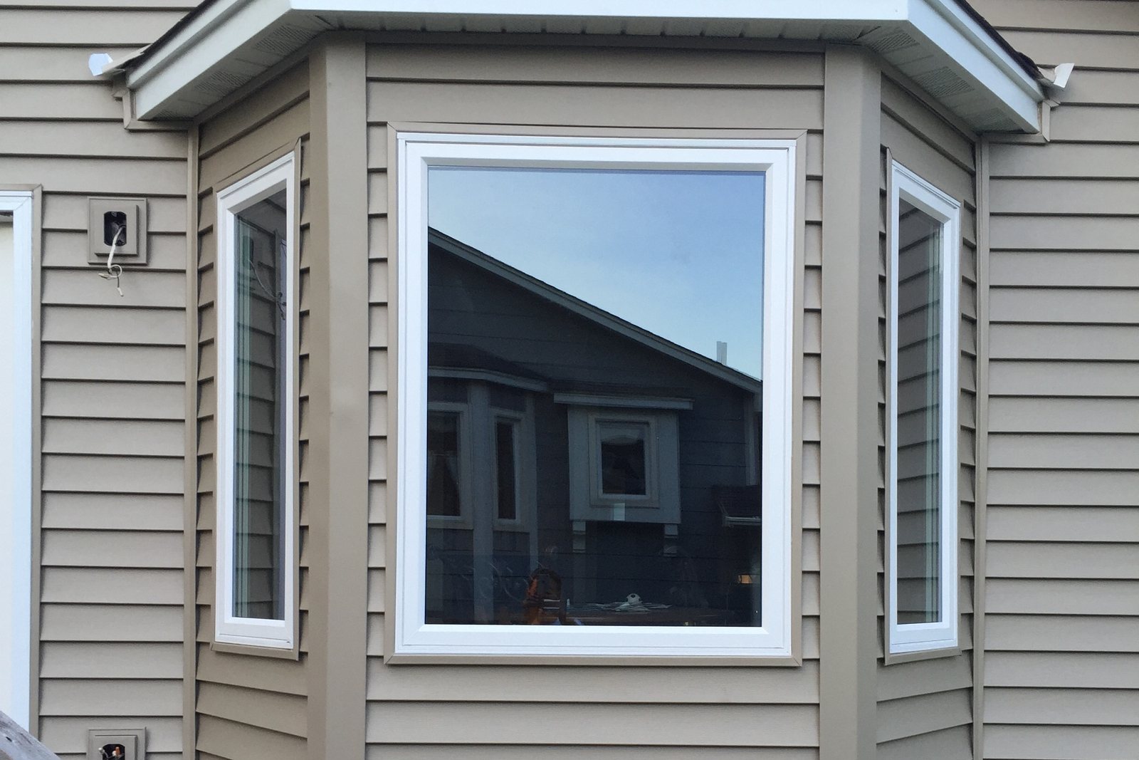 Bay window wrapped in new trim against board and batten siding